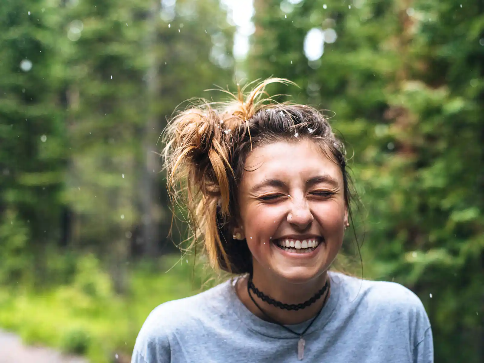 ein-lachendes-maedchen-mit-zerzaustem-haar Ein lachendes Mädchen mit zerzaustem Haar im Freien, umgeben von grünen Bäumen im Wald von HANF SPAR.