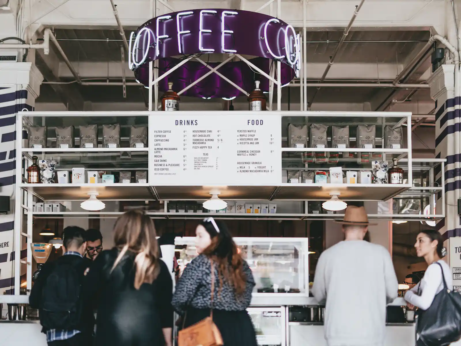 modernes-cafe-mit-kunden-und-coffee-schild Ein belebtes Café mit einem modernen Design, einem beleuchteten "Coffee"-Schild und mehreren Kunden an der Theke. HANF SPAR!
